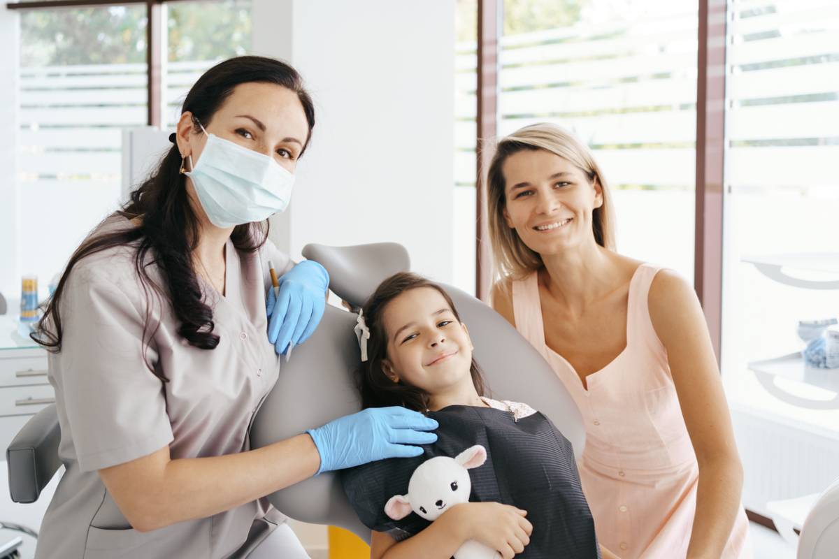 dentist, child patient holding stuffed animal, patient's mother