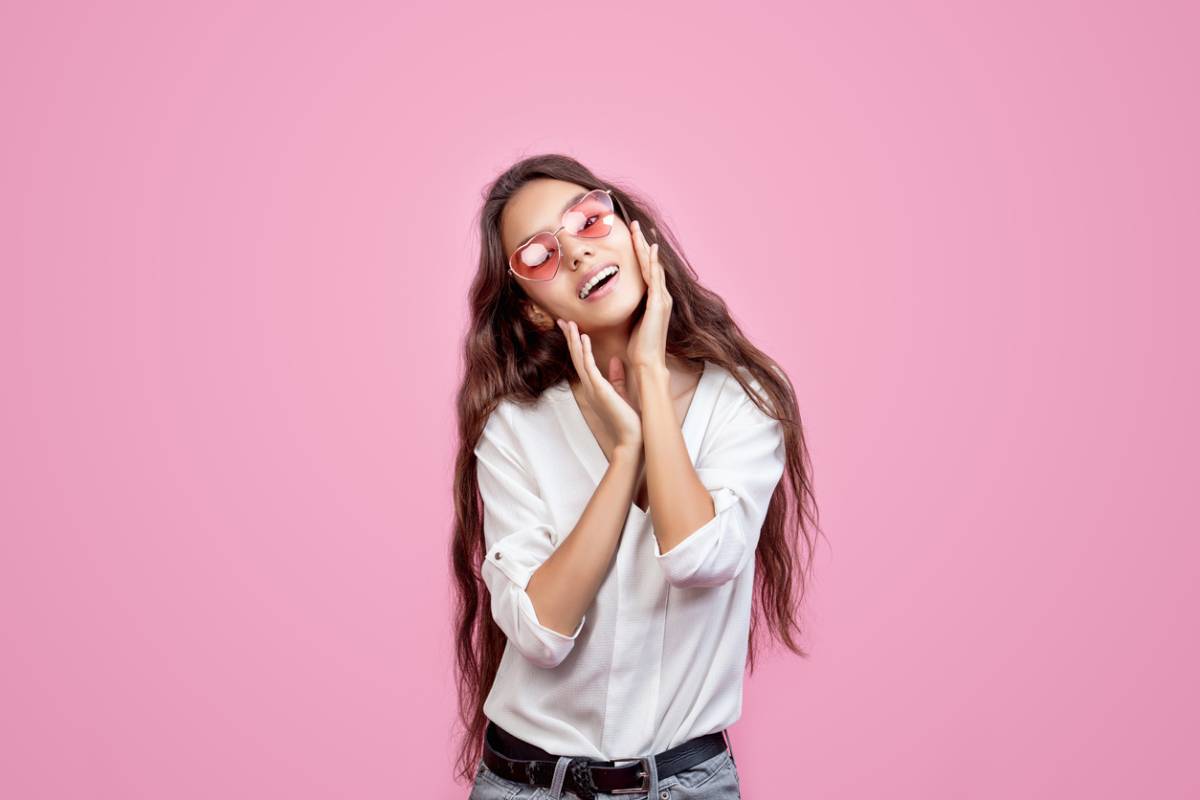 woman smiling against pink background with pink glasses