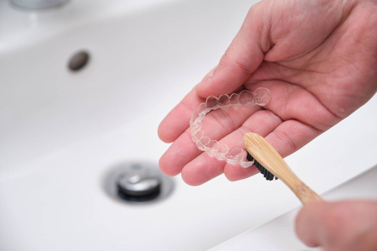 Person cleaning invisalign trays in a sink